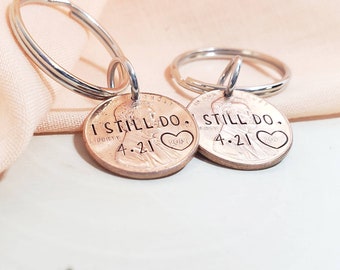 May include: Two silver keychains with a copper penny attached to each. The pennies have the words "I Still Do." engraved on them, along with the date "4.21" and a heart.
