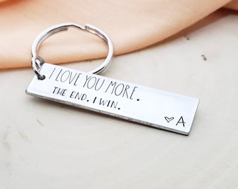 May include: Silver keychain with a rectangular tag that reads "I love you more. The end. I win." with a heart and the letter "A" engraved on the bottom.