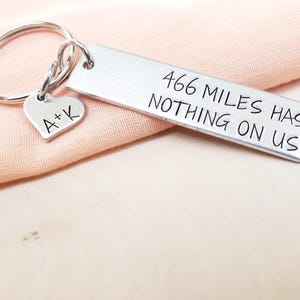 May include: Silver keychain with a heart charm engraved with "A+K" and a rectangular tag engraved with "466 MILES HAS NOTHING ON US".