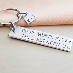 May include: Silver keychain with a heart charm engraved with "K+J" and a rectangular tag engraved with "You're worth every mile between us".