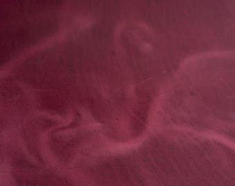 Może przedstawiać: Zbliżenie na głęboki bordowy materiał skórzany o gładkiej, lekko fakturowanej powierzchni. Materiał ma subtelny połysk i miękki, giętki charakter.