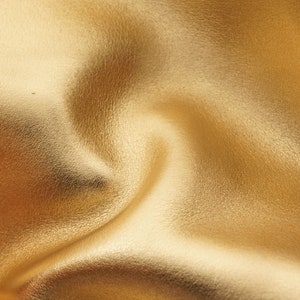 Könnte beinhalten: Nahaufnahme eines glatten, goldenen Lederstoffs mit einem dezenten Glanz. Der Stoff ist zerknittert und gefaltet, wodurch eine strukturierte Oberfläche entsteht.