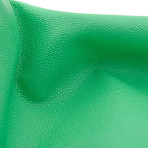May include: Close-up of a bright green textured fabric. The fabric has a pebbled texture and is folded in a curved shape.
