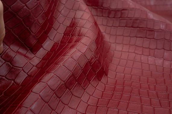Croco leather sheets in dark red color with crocodile patterna very little sheen. High quality leather in crimson red color