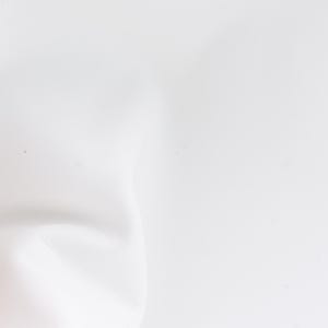 Pode incluir: Um close-up de uma superf&iacute;cie branca, ligeiramente texturizada. A imagem &eacute; predominantemente branca, com sombras e curvas sutis que sugerem um material macio e flex&iacute;vel. A ilumina&ccedil;&atilde;o &eacute; difusa, criando uma est&eacute;tica suave e limpa.