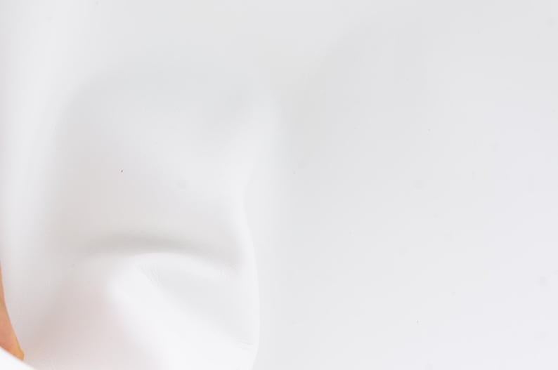 Pode incluir: Um close-up de uma superf&iacute;cie branca, ligeiramente texturizada. A imagem &eacute; predominantemente branca, com sombras e curvas sutis que sugerem um material macio e flex&iacute;vel. A ilumina&ccedil;&atilde;o &eacute; difusa, criando uma est&eacute;tica suave e limpa.