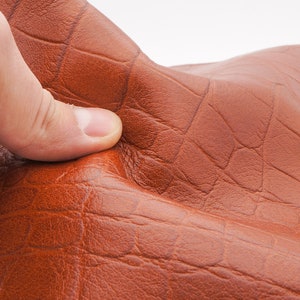 Brown terracotta crocodile pattern real leather sheet .Soft smooth pliable genuine leather piece in terracotta-cognac brown