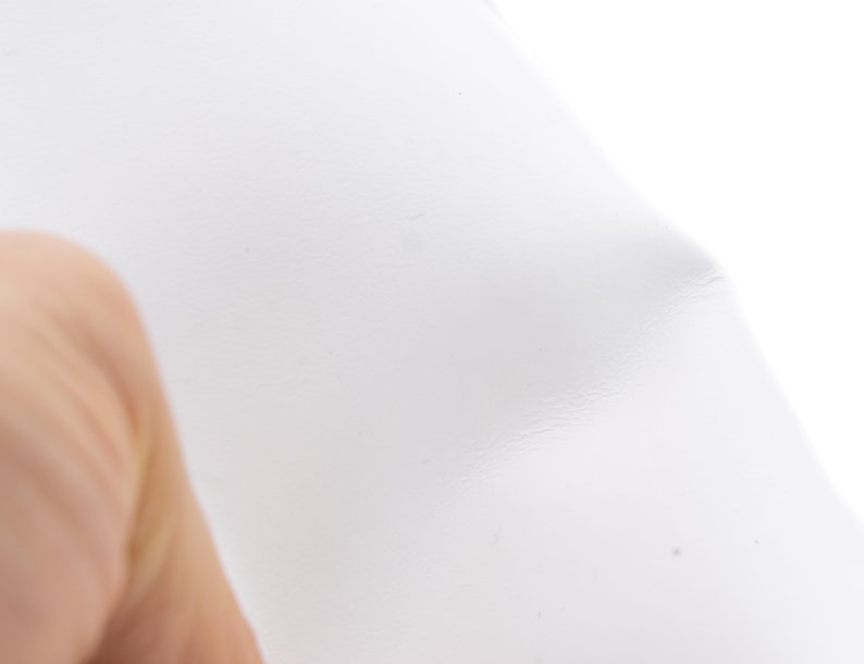 Pode incluir: Um close-up de uma folha de pl&aacute;stico branca transl&uacute;cida. A folha est&aacute; ligeiramente amassada, com varia&ccedil;&otilde;es sutis na textura e no tom. O fundo &eacute; branco brilhante, criando um efeito de alta luminosidade.
