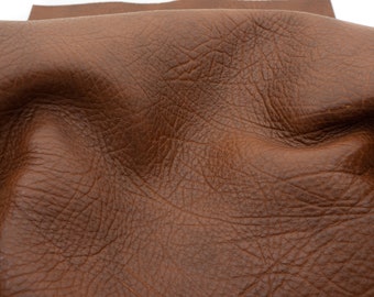 May include: Close-up of a brown leather hide with a textured surface.