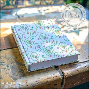 May include: A hardcover notebook with a white cover featuring a repeating pattern of green, orange, and purple floral and geometric designs. The text "Digital File Only" is visible on the cover. The notebook is resting on a stone surface.