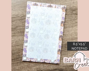 May include: A notepad with a light pink border featuring a pattern of ghosts, pumpkins, high heels, and lipstick. The center has a white sheet with a similar pattern. The notepad measures 8.5" x 5.5".