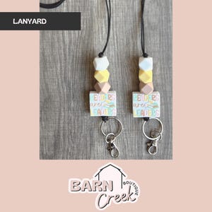 May include: Two black lanyards with colorful silicone beads and a charm with the text "Leaders are Leaders".