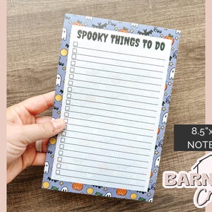 May include: A notepad with a Halloween theme, featuring a list titled "Spooky Things To Do." The notepad has a blue border with ghosts, pumpkins, and bats. The notepad measures 8.5" x 5.5".