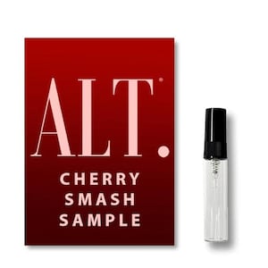 May include: A perfume sample vial with a black cap sits beside a red card. The card features the word "ALT." in large, pale pink letters, with "CHERRY SMASH SAMPLE" written beneath. The card's background is a gradient of red.