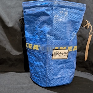 Może przedstawiać: Niebieska, wielorazowa torba na zakupy z logo IKEA i żółtą naszywką z motywem stokrotki z napisem "Daisy Chain, Made in Australia".