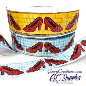 May include: Two rolls of ribbon with a red glitter ruby slipper design. The top roll is yellow with a gingham pattern and the bottom roll is blue with a gingham pattern. The ribbon is perfect for crafting, decorating, and adding a touch of whimsy to any project.