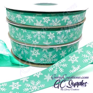 May include: A roll of teal blue ribbon with white snowflake designs. The ribbon is on a white spool and is available for purchase from Gerry Creations.