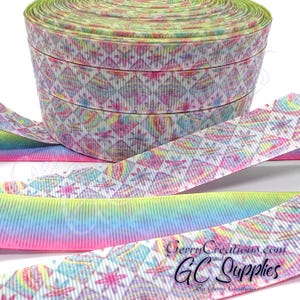 May include: A roll of patterned ribbon with a geometric design in pink, blue, yellow, and white. The ribbon is a grosgrain style with a textured surface. The text "Gerry Creations.com" and "GC Supplies" is visible on the ribbon.