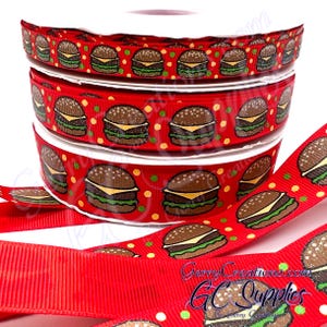 May include: Red ribbon spools with a repeating pattern of cartoon hamburgers. The burgers have brown buns, green lettuce, and yellow cheese. The ribbon also features small yellow and green polka dots. The text "GerryCreations.com GC Supplies" is visible.