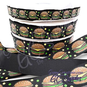 May include: Black and green ribbon with a repeating pattern of mini cheeseburgers with yellow cheese, green lettuce, and brown burger patties. The ribbon is layered on top of itself, showing the pattern repeating.