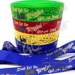 May include: A stack of colorful ribbons with the text "Don't Let the Muggles Get You Down." The ribbons are green, red, yellow, and blue. The blue ribbon is unrolled and lies in front of the stack.