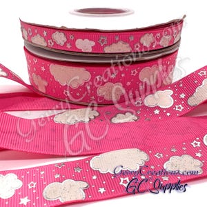 May include: Pink ribbon spools with a repeating pattern of silver clouds and stars. The ribbon has a textured, ribbed surface. The text "GerryCreations.com GC Supplies" is visible on the ribbon. Ideal for crafting and gift wrapping.