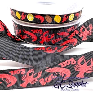 May include: Black and red ribbon with a repeating pattern of red crawfish and the word "BOIL" in red. The ribbon is on a white spool.