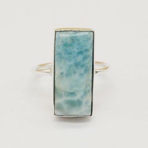 May include: A silver ring with a light blue rectangular gemstone. The gemstone has a cloudy, marbled pattern.