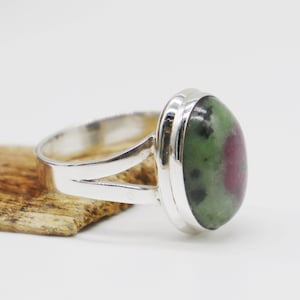 May include: A silver ring with a green and pink oval gemstone set in a bezel setting.