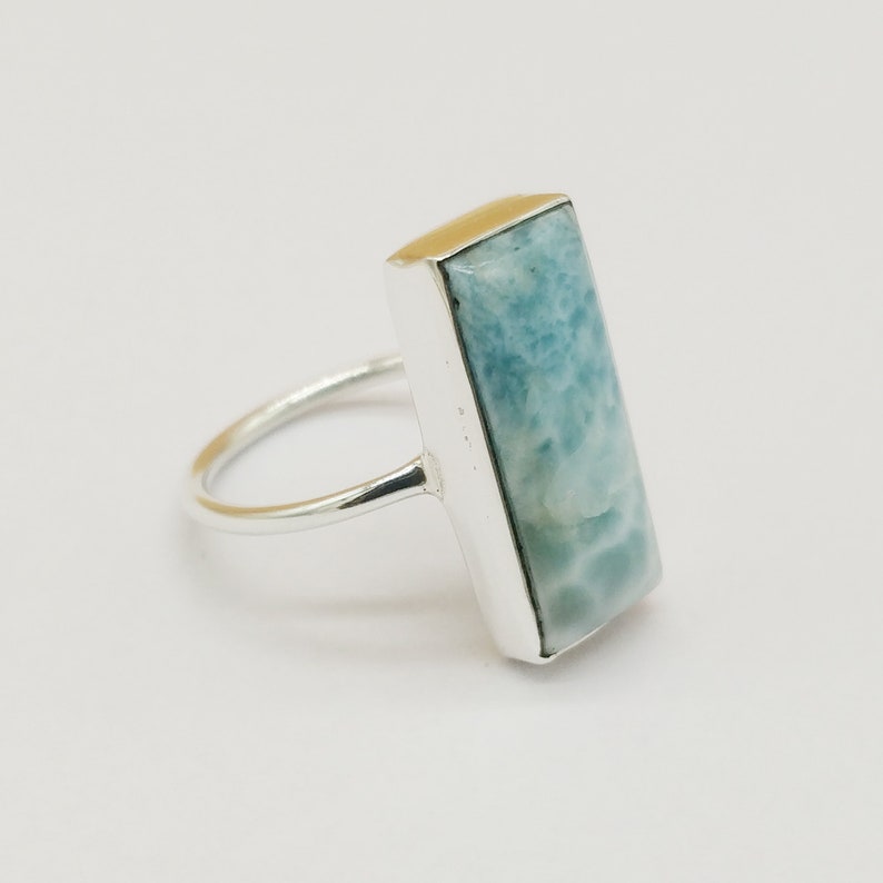 May include: A silver ring with a light blue rectangular gemstone. The gemstone has a marbled pattern.