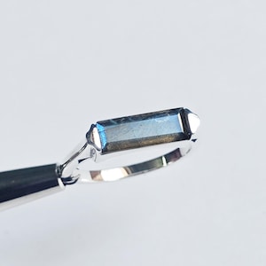 May include: A silver ring with a rectangular blue labradorite gemstone.