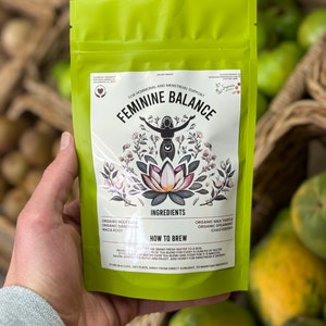 May include: Green pouch with white text that reads "Feminine Balance" for hormonal and menstrual support. The pouch contains a blend of organic herbs including holy basil, dandelion, maca root, milk thistle, spearmint, and chasteberry.