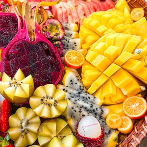 May include: A colorful fruit platter with watermelon, mango, dragon fruit, kiwi, and kumquats. The platter is arranged in a woven basket with a pink and white floral design. The text "Los Angeles Produce" is visible in the lower right corner.