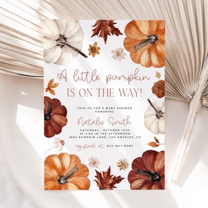 Pumpkin baby shower invitation with orange, copper and white pumpkin and autumn florals and leaves placed on a table.