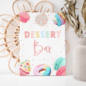 May include: A printable sign for a dessert bar with a white background and colorful polka dots. The sign says "Dessert Bar" in rainbow letters with a pink cupcake, donut, and macarons on the bottom.