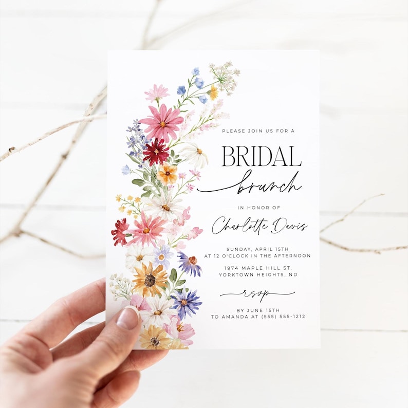 Bridal shower invitation with colorful wildflowers arch and cursive writing. The invite includes watercolor illustration of soft summer wildflowers in pink, yellow, blue, purple, red and white tones. The text includes bridal brunch as it's title.