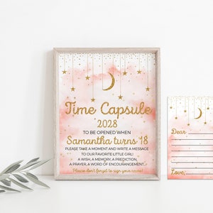 Può includere: Una carta di capsula del tempo rosa e oro con una luna crescente e stelle. La carta dice "Time Capsule 2028 To be opened when Samantha turns 18". C'è una carta più piccola con righe per scrivere un messaggio.