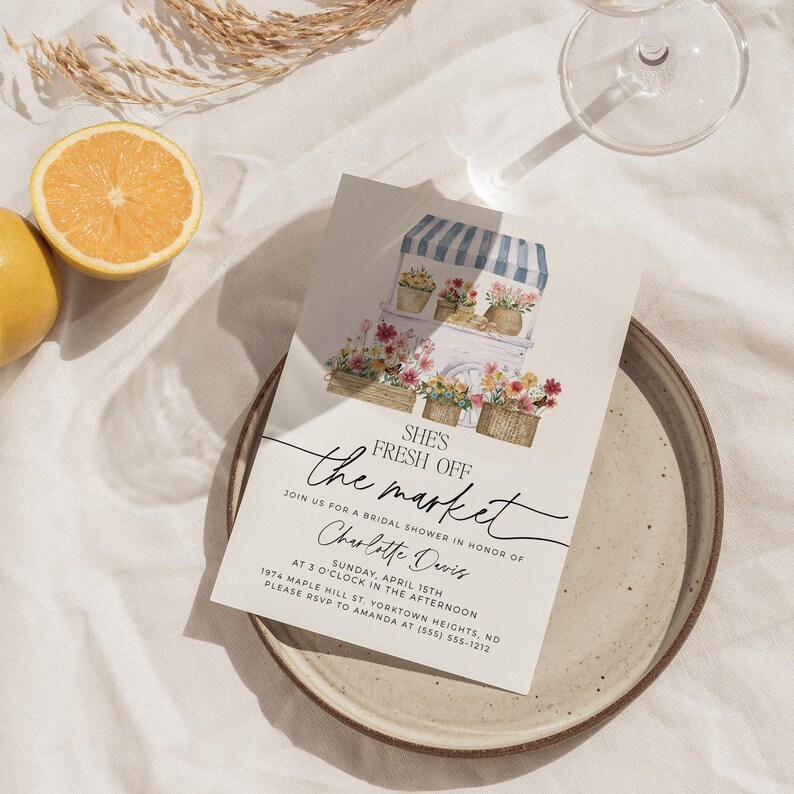 Op de afbeelding: Een witte kaart met een bloemillustratie van een bloemenkraam met een blauw-wit gestreept luifel. De tekst "SHE'S FRESH OFF the market" is geschreven in zwarte cursieve letters. De tekst "JOIN US FOR A BRIDAL SHOWER IN HONOR OF Charlotte Davis" is geschreven in zwarte tekst. De tekst "SUNDAY, APRIL 15TH AT 3 O'CLOCK IN THE AFTERNOON 1974 MAPLE MILL ST. YORKTOWN HEIGHTS, NO PLEASE RSVP TO AMANDA AT (555) 555-1212" is geschreven in zwarte tekst.