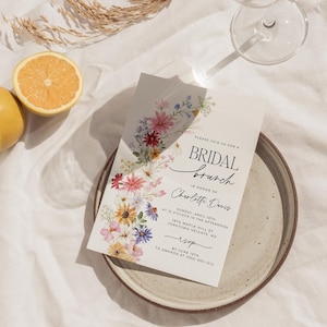 Bridal shower invitation with colorful wildflowers arch and cursive writing. The invite includes watercolor illustration of soft summer wildflowers in pink, yellow, blue, purple, red and white tones. The text includes bridal brunch as it's title.