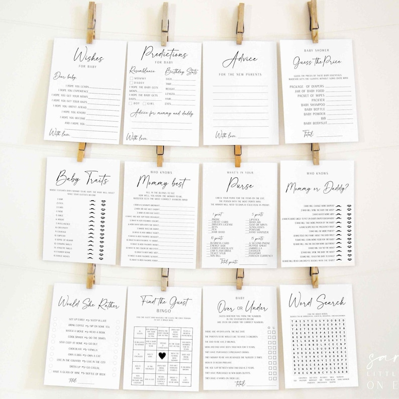 Puede incluir: Un conjunto de tarjetas de juegos para baby shower, impresas en tinta negra sobre cartulina blanca, se exhiben. Las tarjetas est&aacute;n sujetas con pinzas de madera. Los juegos incluyen "Deseos", "Predicciones", "Consejos", "Rasgos del beb&eacute;" y "B&uacute;squeda de palabras".