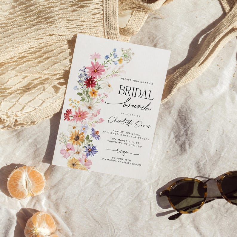Bridal shower invitation with colorful wildflowers arch and cursive writing. The invite includes watercolor illustration of soft summer wildflowers in pink, yellow, blue, purple, red and white tones. The text includes bridal brunch as it's title.