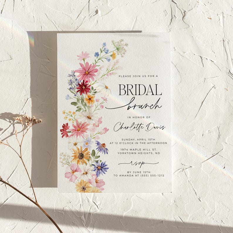 Bridal shower invitation with colorful wildflowers arch and cursive writing. The invite includes watercolor illustration of soft summer wildflowers in pink, yellow, blue, purple, red and white tones. The text includes bridal brunch as it's title.