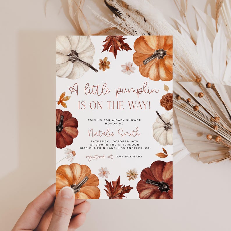 Pumpkin baby shower invitation with orange, copper and white pumpkin and autumn florals and leaves handheld.