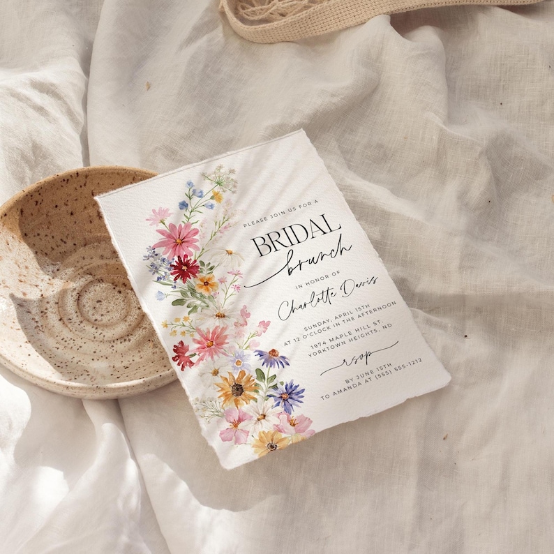 Bridal shower invitation with colorful wildflowers arch and cursive writing. The invite includes watercolor illustration of soft summer wildflowers in pink, yellow, blue, purple, red and white tones. The text includes bridal brunch as it's title.