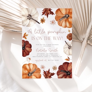 Pumpkin baby shower invitation with orange, copper and white pumpkin and autumn florals and leaves placed on a table.