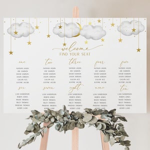 May include: A white seating chart with gold lettering and illustrations of clouds, stars, and a crescent moon. The chart is titled "Welcome Find Your Seat" and lists ten tables with guest names.