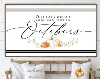 May include: A white framed print with black stripes and the text "I'm so glad I live in a world, where there are Octobers."  The print features a stylized cursive font and three pumpkins, one white and two orange.