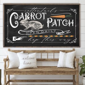 May include: A black chalkboard sign with white lettering that reads "Cottontails Carrot Patch Open Daily Hop This Way". The sign features a drawing of a rabbit and carrots.