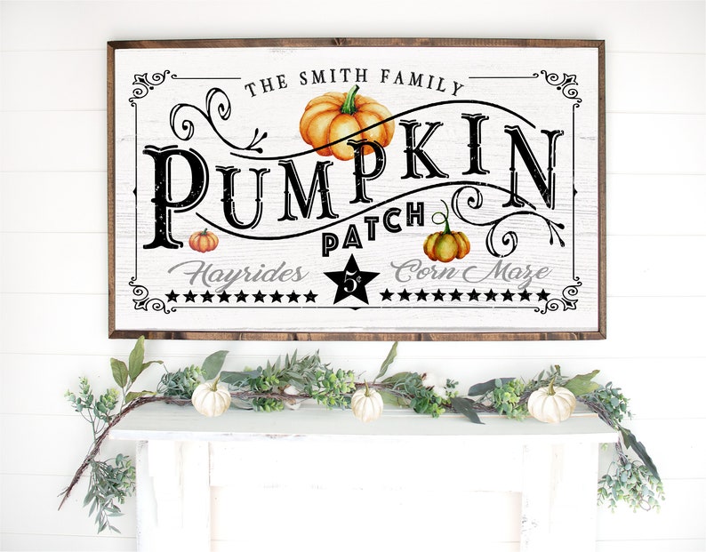 May include: A white wooden sign with black text that reads "The Smith Family Pumpkin Patch Hayrides 5&cent; Corn Maze". The sign has a brown wooden frame and features a stylized pumpkin design with orange and green accents.