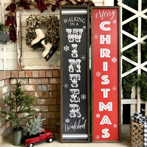 May include: Two wooden signs with black and red paint. The sign on the left says "Walking in a Winter Wonderland" and the sign on the right says "Merry Christmas".